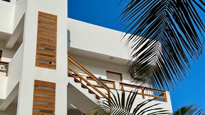 Een modern gebouw met een witte gevel, houten lamellen aan de buitenkant en een balkon met houten leuningen.