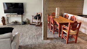 Una sala moderna con un televisor, una mesa de comedor de madera y sillas rojas.