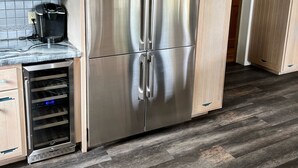 Una cocina con armarios de madera, un refrigerador de acero inoxidable y un enfriador de vino empotrado.
