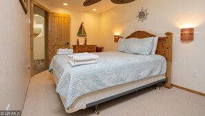 Un dormitorio con cama, ventilador de techo, mesita de noche y lámpara de pared.