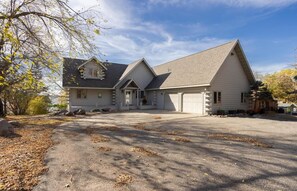 A two-story log cabin with a garage, a covered front porch, and a driveway.