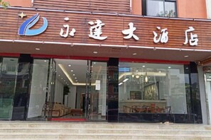 A hotel entrance with a modern design, featuring a glass facade and a red carpet leading to the entrance. - Yongda Hotel (Hengfeng)