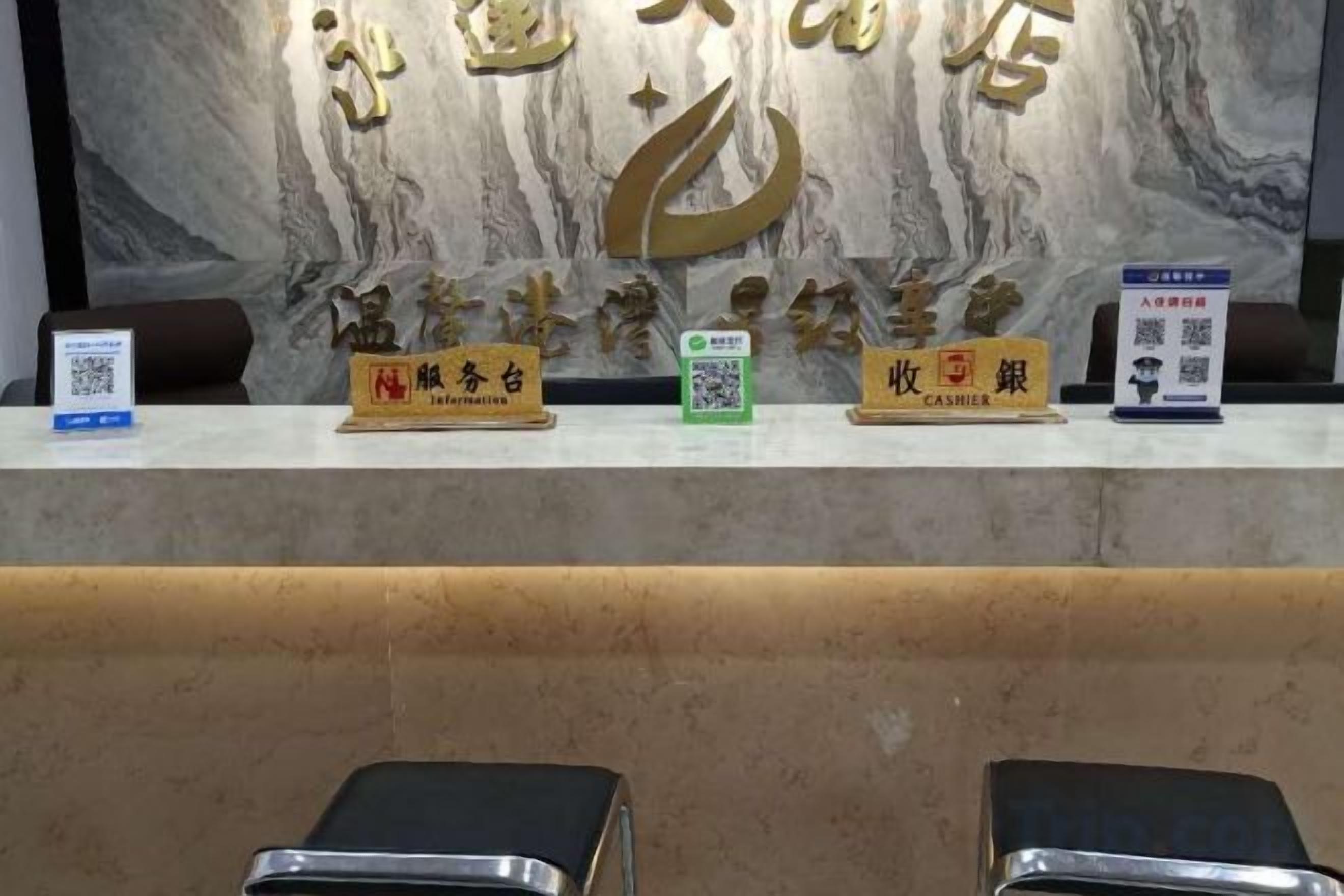 A reception desk with a marble wall background, nameplates for reception and cashier, and a QR code for information.