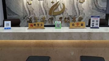 A reception desk with a marble wall background, nameplates for reception and cashier, and a QR code for information.