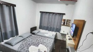 A hotel room with a bed, a desk with a computer, a TV, and a window with curtains. - Hotel Real Koerich 24h (Rio do Sul)