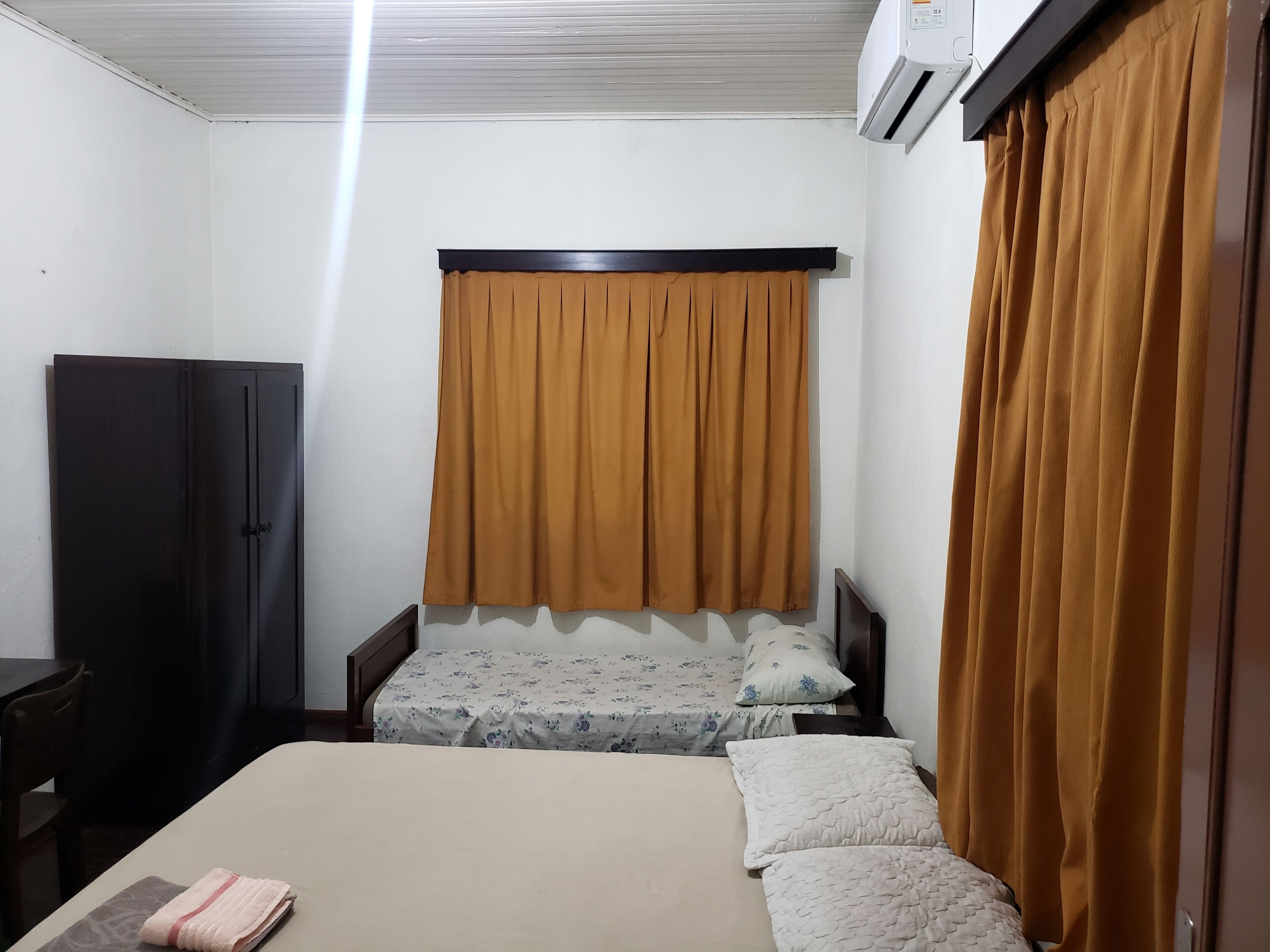 A bedroom with a bed, a wardrobe, and an air conditioning unit.