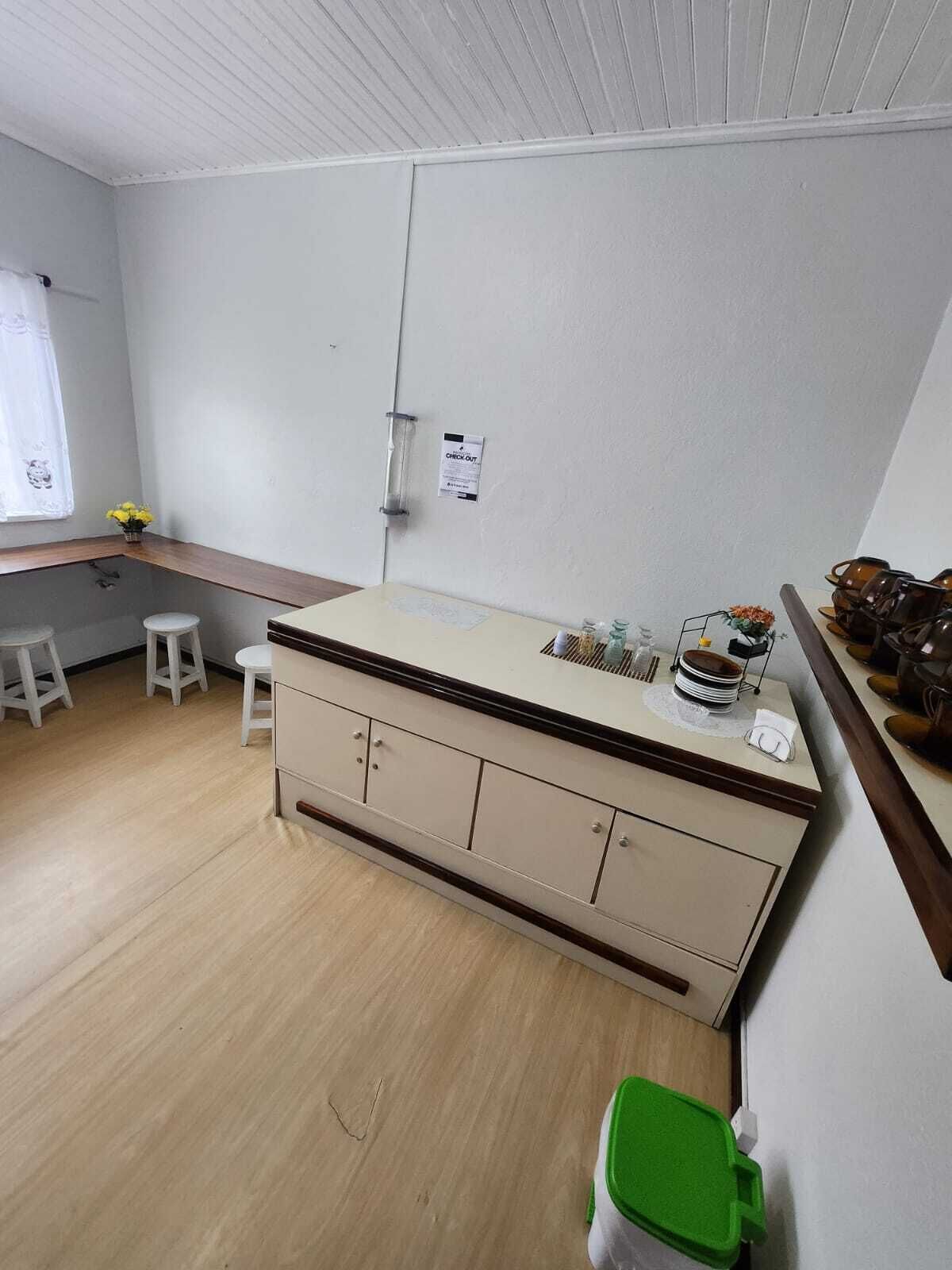 A small kitchen with a wooden countertop, white cabinets, and a window with a curtain.