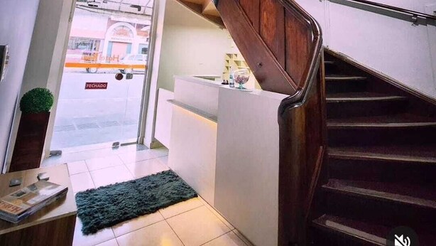 A modern interior with a wooden staircase, a reception desk, and a view of the street outside. - Hotel Real Koerich 24h (Rio do Sul)