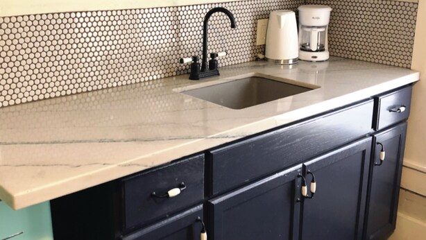 Una cucina con lavello, macchina del caffè e schienale piastrellato.