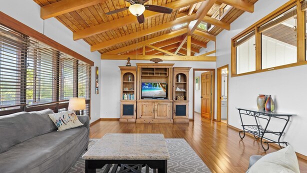 A spacious living room with a wooden ceiling, a television, and a cozy seating area. - Walk to Beach! HUGE 5 bedroom, 5 bath with Pool!! (Kailua-Kona)