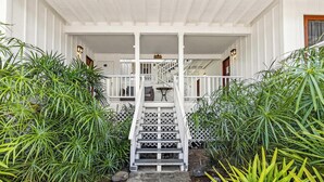A white wooden staircase leading to a porch with a railing, surrounded by lush green plants. - Walk to Beach! HUGE 5 bedroom, 5 bath with Pool!! (Kailua-Kona)