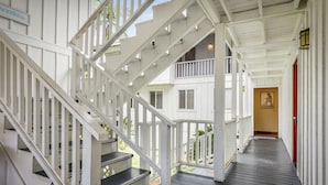 A wooden staircase leading to a second-floor balcony with a white railing. - Walk to Beach! HUGE 5 bedroom, 5 bath with Pool!! (Kailua-Kona)