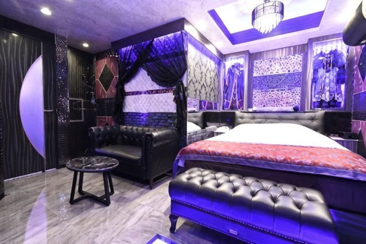 A room with a large bed, a sofa, and a small table.