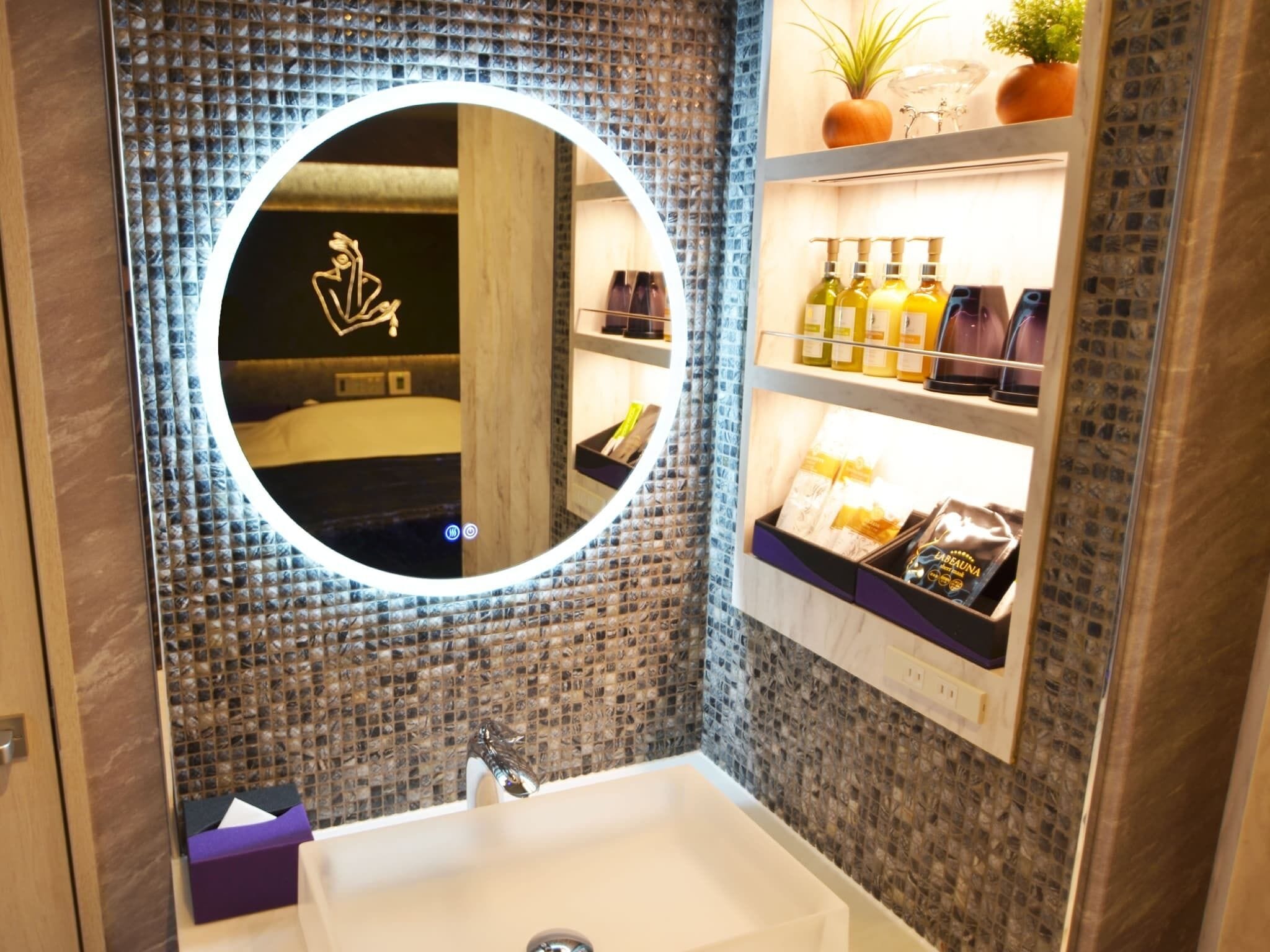 A bathroom with a round mirror, a sink, and shelves with toiletries.