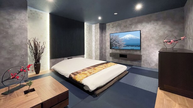 Une chambre à coucher moderne avec un lit, un téléviseur fixé au mur et une table de chevet en bois.
