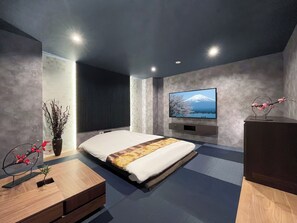 Une chambre à coucher moderne avec un lit, un téléviseur fixé au mur et une table de chevet en bois.