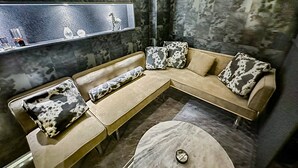 Un espace de détente moderne avec un canapé d’angle, une table basse ronde et un sol en marbre.