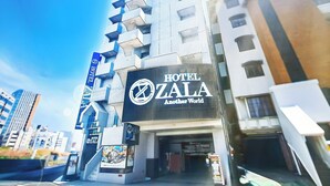 Un hôtel moderne, avec une enseigne bien visible indiquant : « HÔTEL ZALA, un monde à part ».