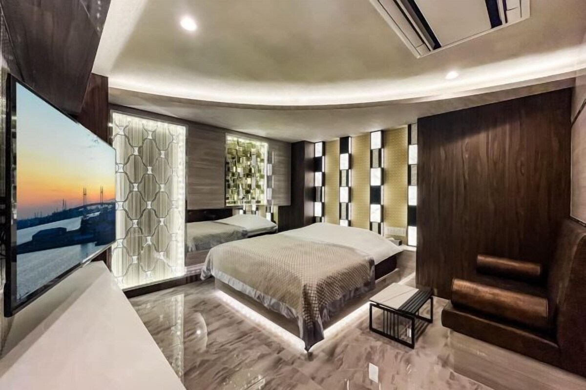 Une chambre moderne avec un plafond incurvé, un grand lit, une télévision et une vue sur le paysage urbain.