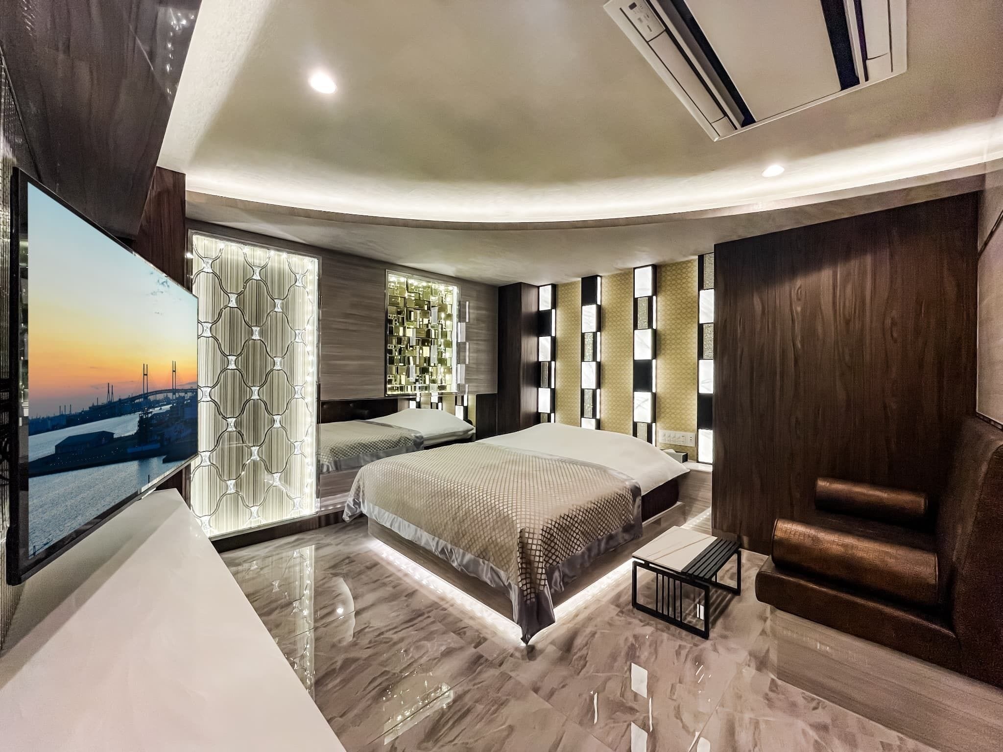 A modern bedroom with a large bed, a TV, and a cityscape view.