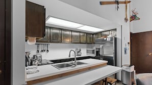 Une cuisine moderne dotée d’un grand îlot central, d’appareils électroménagers en acier inoxydable et d’armoires en bois.