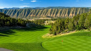 A golf course with a flag, surrounded by mountains and trees. - Mountain View Hideaway, 14 Min to Glenwood Hot Springs, 2 King Beds, Golf Views (New castle)