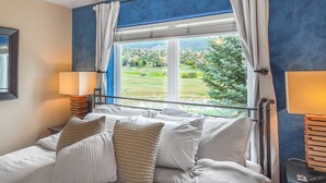 A bedroom with a bed, pillows, a nightstand, a lamp, and a window with curtains. - Mountain View Hideaway, 14 Min to Glenwood Hot Springs, 2 King Beds, Golf Views (New castle)