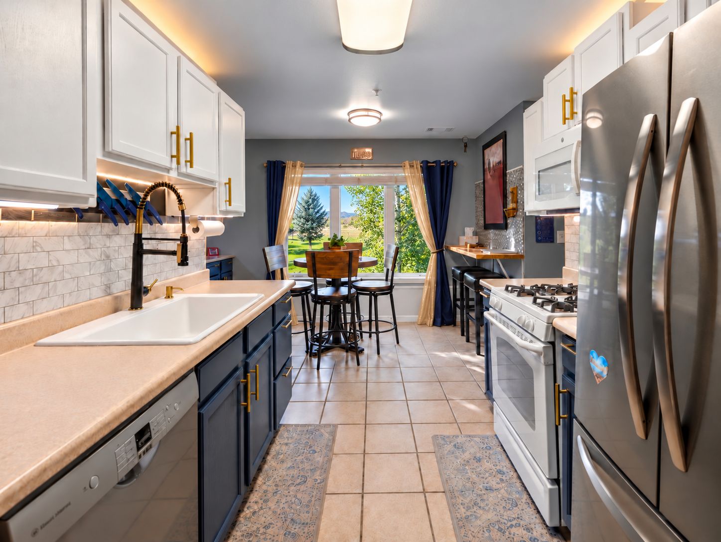 A modern kitchen with white cabinetry, stainless steel appliances, and a view to the outdoors.