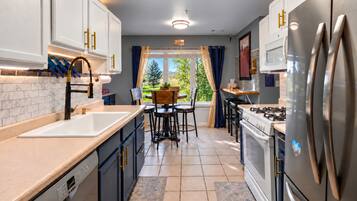 A modern kitchen with white cabinetry, stainless steel appliances, and a view to the outdoors.