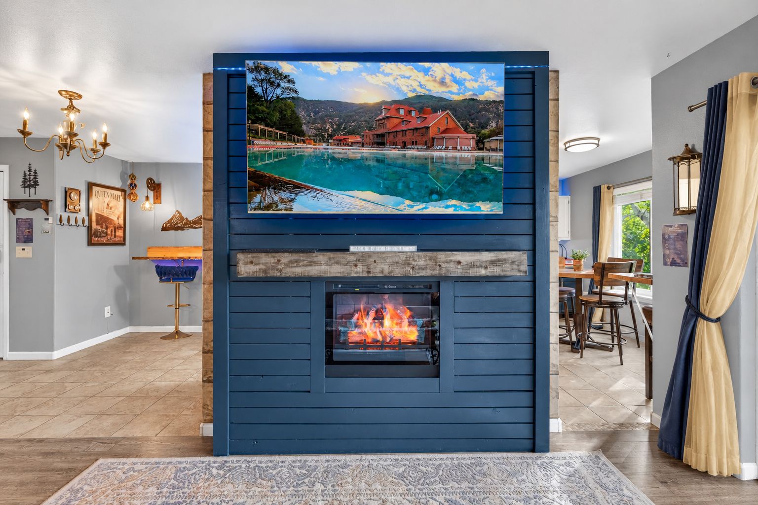 A living room with a fireplace, a mounted TV, and a dining area.