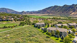 A residential area with houses, a golf course, and mountains in the background. - Mountain Views • 2 King Beds • 2 Baths • Sleeps 8 • 14 Min to Glenwood Springs (New castle)