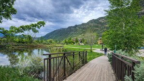 A wooden boardwalk leading to a park with a lake, surrounded by greenery and hills. - Mountain View Hideaway, 14 Min to Glenwood Hot Springs, 2 King Beds, Golf Views (New castle)