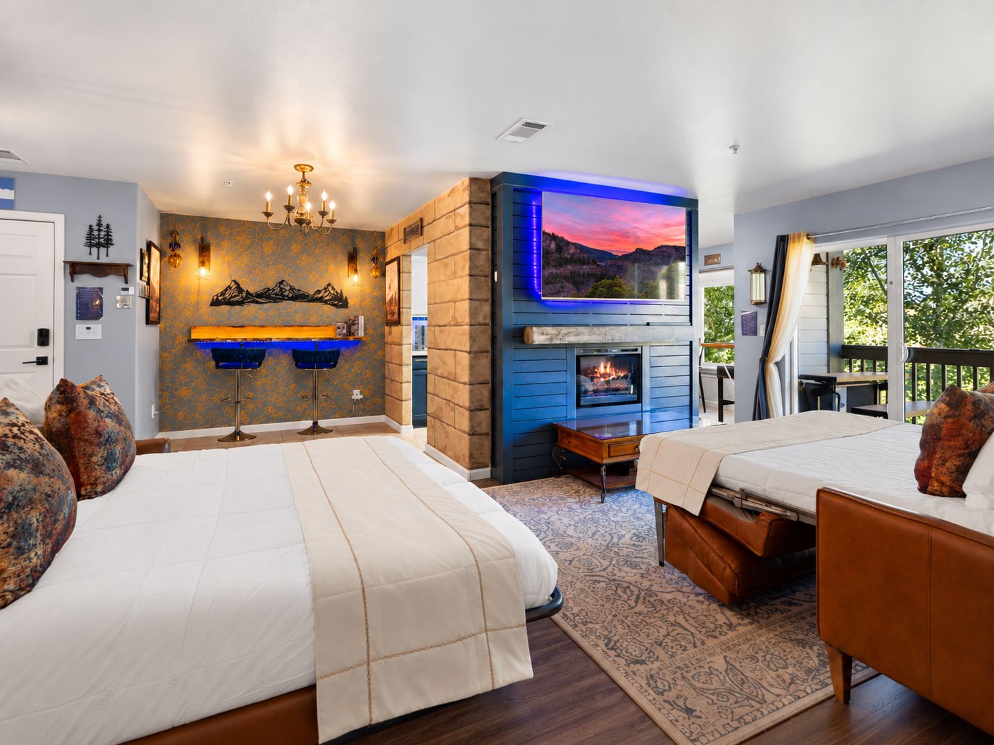 A hotel room with two beds, a fireplace, a television, and a view of the outdoors.