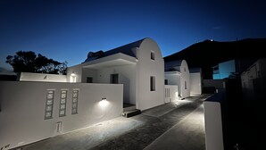Un edificio moderno blanco con techo curvo, un pequeño porche y un sendero que lleva a la entrada.