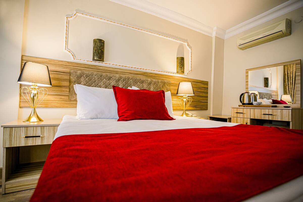 A hotel room with a large bed, two bedside tables with lamps, a mirror, and a dresser.