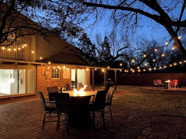 An outdoor patio with a round table, chairs, and a fire feature.