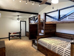 A room with a bunk bed, a desk, and a chair. There is a ceiling fan and a light fixture.