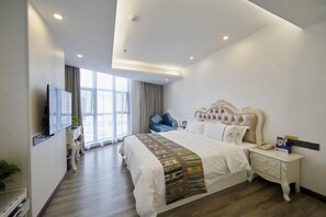 Une chambre d’hôtel moderne, dotée d’un grand lit, d’une table de chevet, d’un téléviseur fixé au mur et d’une fenêtre avec des rideaux.