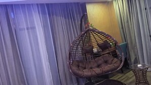 Une pièce avec un fauteuil suspendu, une petite table et des rideaux.