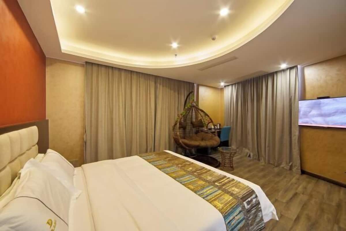 Una camera d'albergo con un letto, una poltrona sospesa, una televisione e tende.