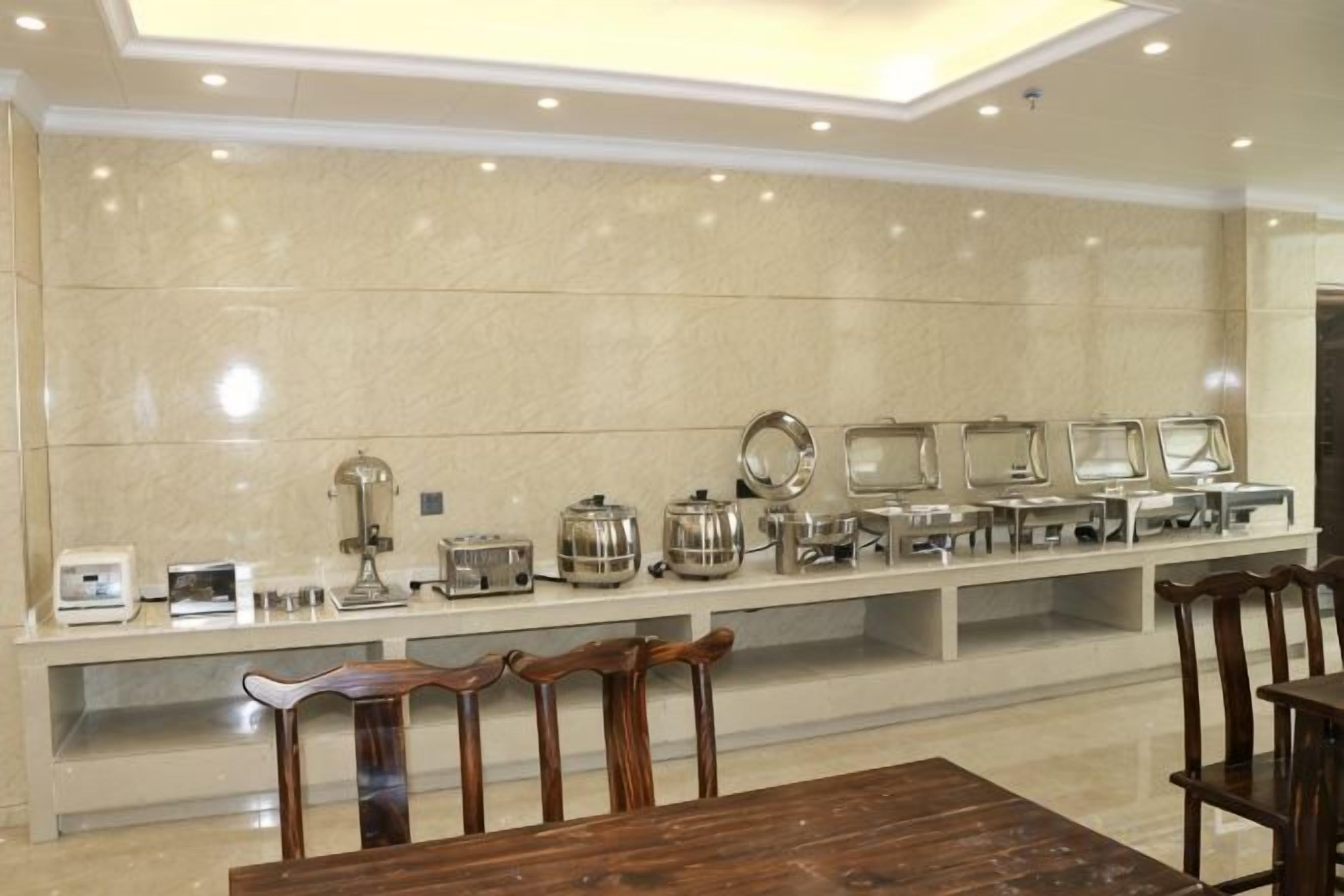 A buffet setup with a long counter, various food appliances, and seating arrangements.