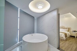Une salle de bain moderne avec un grand lavabo rond, un miroir et un luminaire fixé au plafond.