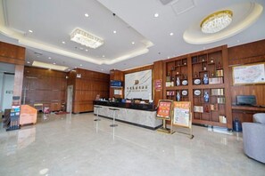 A hotel lobby with a reception desk, wooden paneling, a chandelier, and a wall with framed items. - Holiday Inn Bali (Rong County)