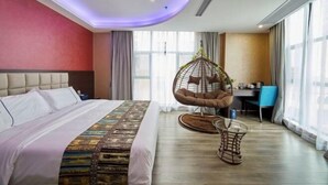 Une chambre d’hôtel avec un lit, un fauteuil suspendu, un bureau et de grandes fenêtres.