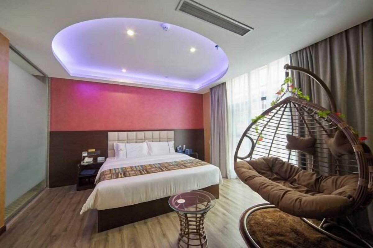Une chambre d’hôtel moderne avec un lit, un fauteuil suspendu, une petite table et un luminaire au plafond.