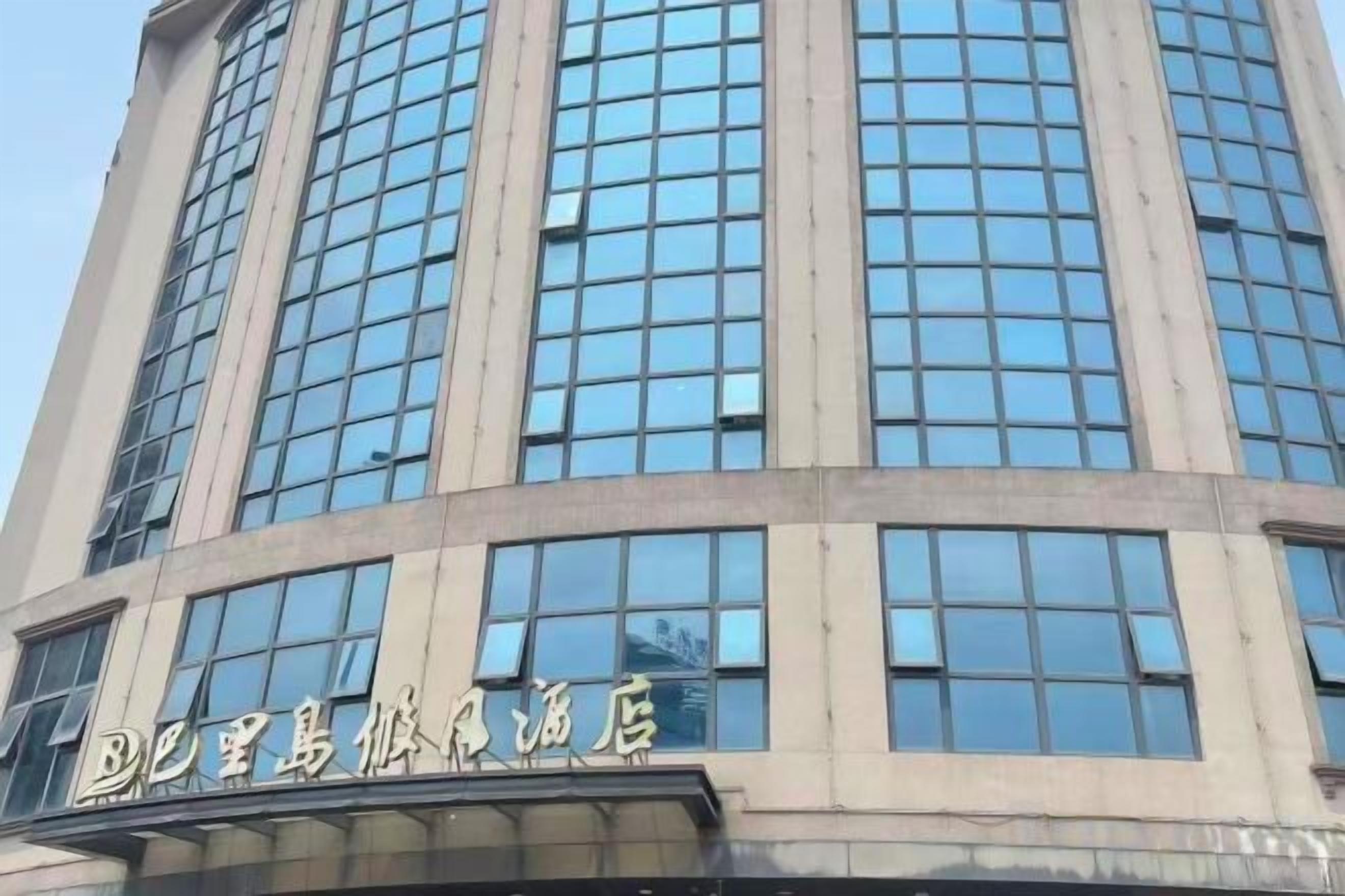 A tall building with a series of windows and a sign with Chinese characters.