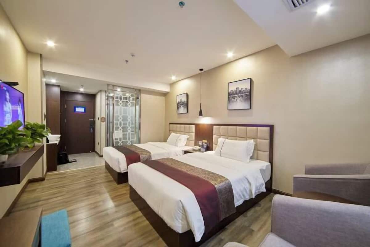Una camera d'albergo con due letti, televisione, scrivania e angolo salotto.