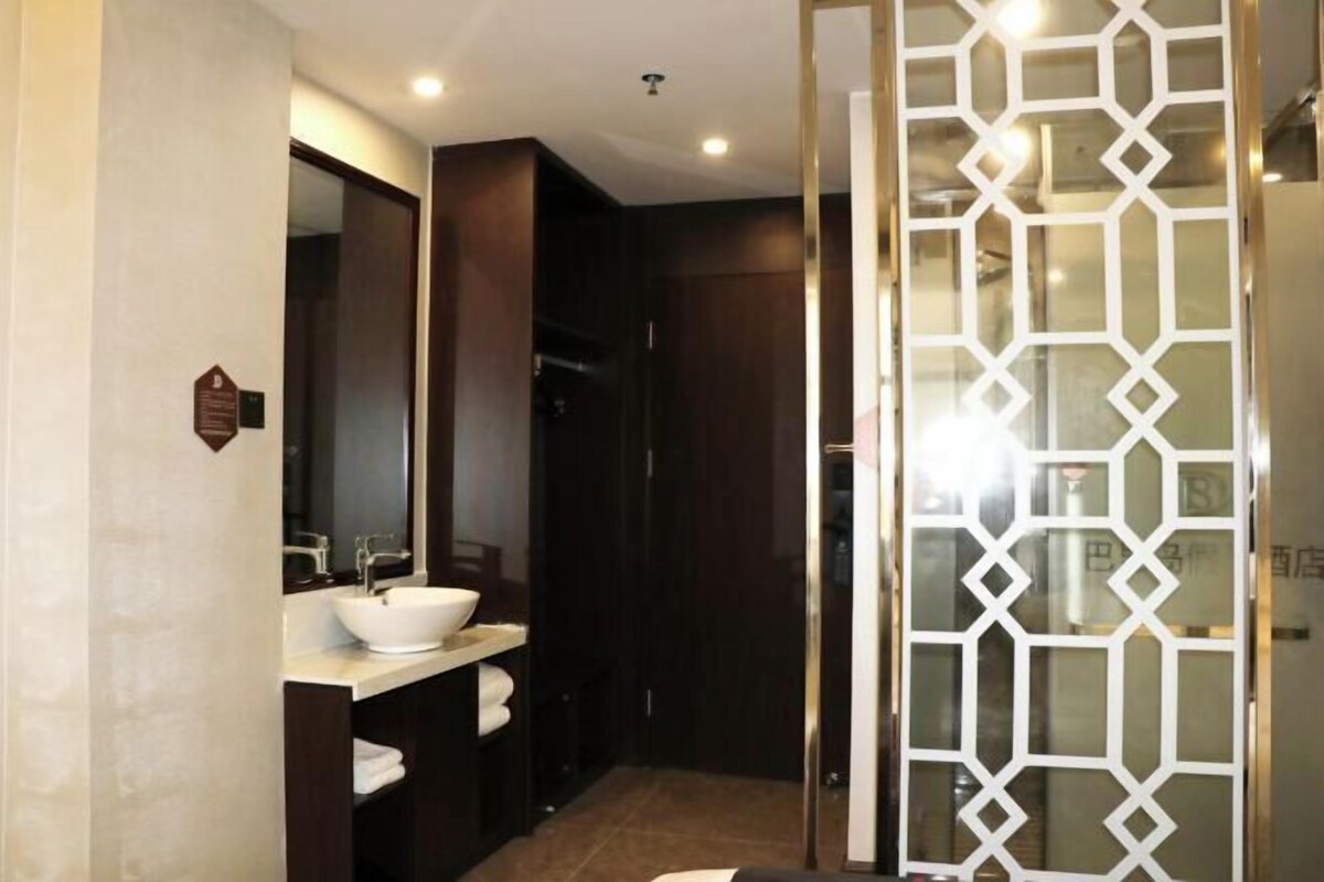Une salle de bain moderne avec un grand miroir, un lavabo blanc et des meubles en bois foncé.