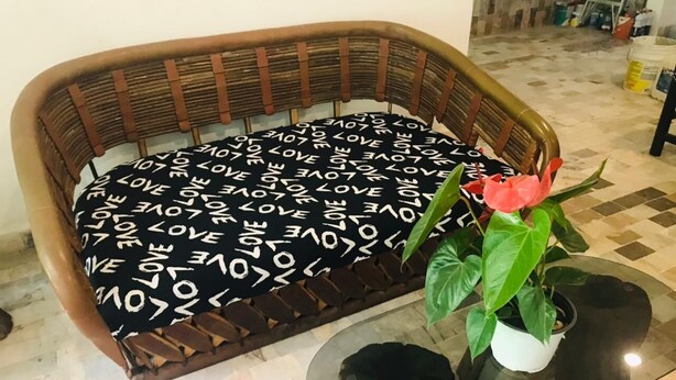 A curved wicker sofa with a black and white patterned cushion, a glass coffee table with a potted plant, and a tiled floor. - Apartment in Diamante area Acapulco (Acapulco)