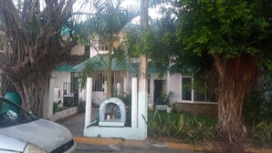 A residential building with a gated entrance, a small shrine or altar, and a car parked in front. - Apartment in Diamante area Acapulco (Acapulco)